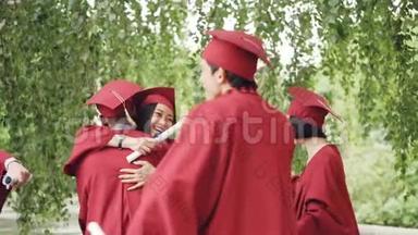毕业典礼后，手持毕业证书，戴着传统帽子，快乐的人们拥抱在一起
